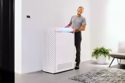 Ein Monteur stellt den Stromspeicher an eine ideale Stelle des Wohnbereichs, wo genug Luftzirkulation und Belüftung herrscht.